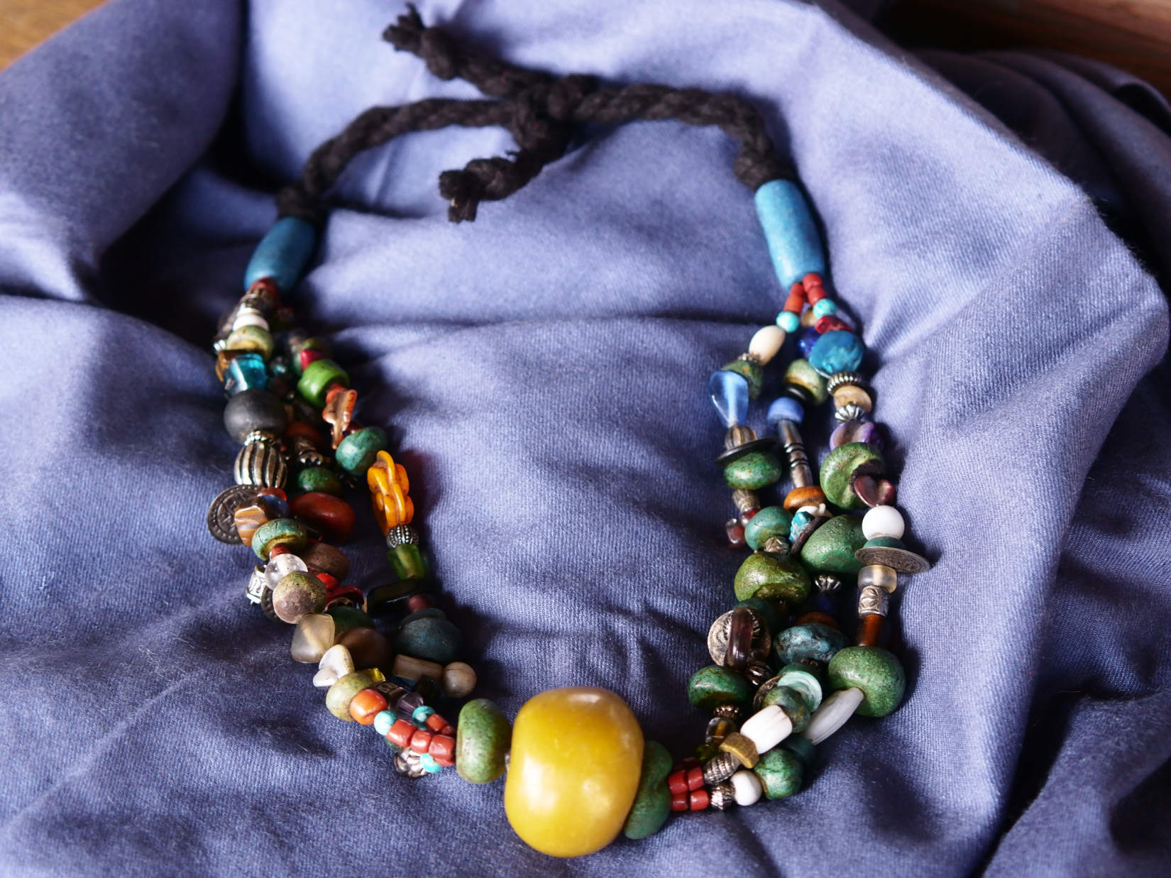 Collana tribale Amazigh, Berbera. Fatta a mano da artigiani berberi tradizionali con perline in ceramica, cristalli, pelle, pietre, corna, resine vegetali naturali e alcune piccole monete vecchie. La pietra centrale di un colore giallo intenso è di diametro 4cm circa, è leggermente ovalizzata. Pezzo unico di origine tribale , disponibili altri modelli oltre a quelli fotografati.  lunghezza 80cm, peso 230 gr