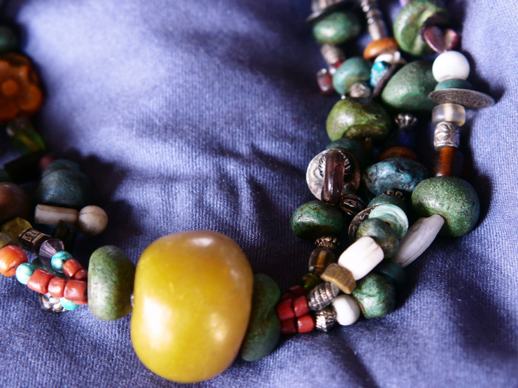 Collana tribale Amazigh, Berbera. Fatta a mano da artigiani berberi tradizionali con perline in ceramica, cristalli, pelle, pietre, corna, resine vegetali naturali e alcune piccole monete vecchie. La pietra centrale di un colore giallo intenso è di diametro 4cm circa, è leggermente ovalizzata. Pezzo unico di origine tribale , disponibili altri modelli oltre a quelli fotografati.  lunghezza 80cm, peso 230 gr