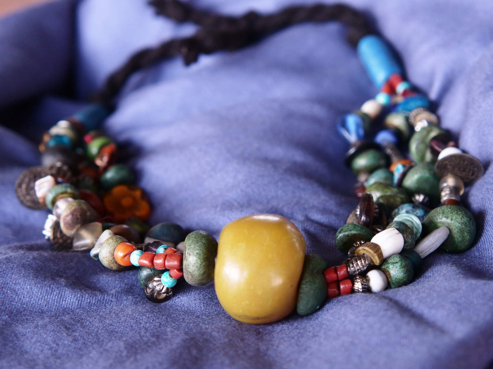 Collana tribale Amazigh, Berbera. Fatta a mano da artigiani berberi tradizionali con perline in ceramica, cristalli, pelle, pietre, corna, resine vegetali naturali e alcune piccole monete vecchie. La pietra centrale di un colore giallo intenso è di diametro 4cm circa, è leggermente ovalizzata. Pezzo unico di origine tribale , disponibili altri modelli oltre a quelli fotografati.  lunghezza 80cm, peso 230 gr