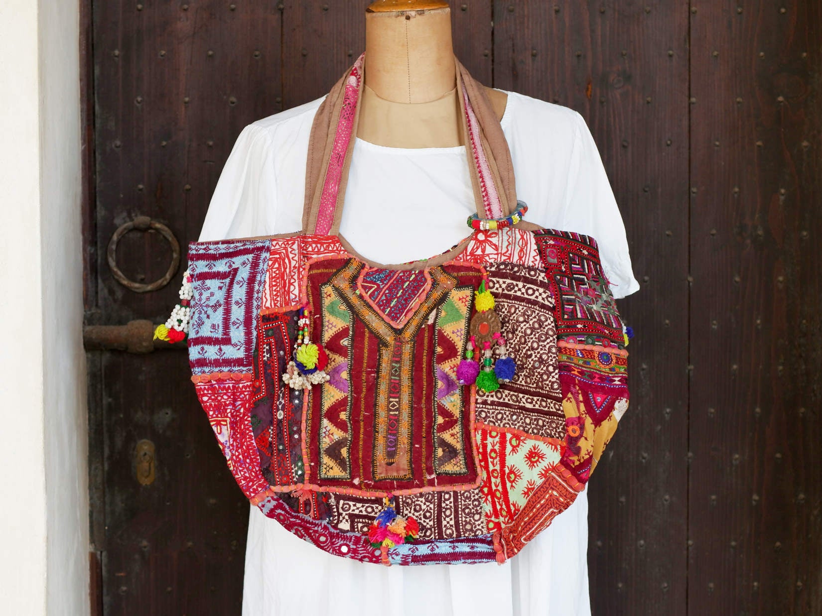 borsa indiana patchwork  tutti i pezzi che la compongono sono elementi in tessuto ricamati con specchietti ,pom pom, ecc... ricavati da vecchi tessuti rajasthani  pezzo unico lavorato interamente a mano  chiusura con cerniera ed interno foderato  lavorata in ogni angolo e lato .  50 x 35 x 15 cm esclusi manici manici 35 cm