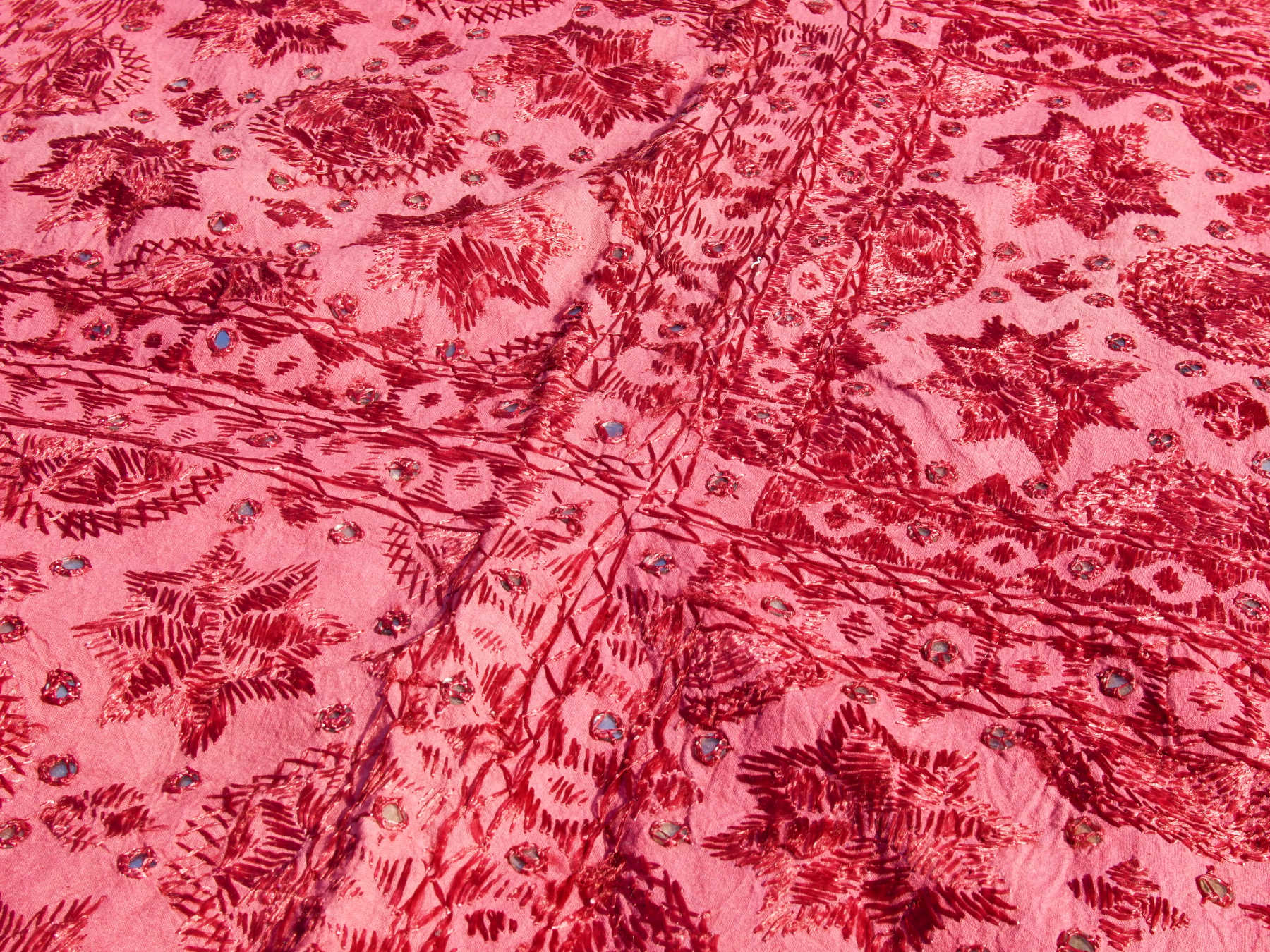 Telo Indiano in cotone doppio strato, ricamato tono su tono con specchietti,  di color rosso. Può essere impiegato come copridivano, copriletto, tovaglia o tessuto da appendere a parete. Dimensioni 210x245cm