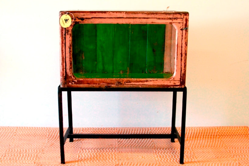 Vetrina, credenza , base indiana con basamento in metallo, vetro frontale e laterale. Usato come vetrina in negozio, apertura frontale a ribalta.  Dipinto interamente nella parte esterna la finitura è sbiancata, nella parte interna di verde intenso. Databile prima metà del '900. Pezzo unico. Dimensioni 75x40xh95cm. 