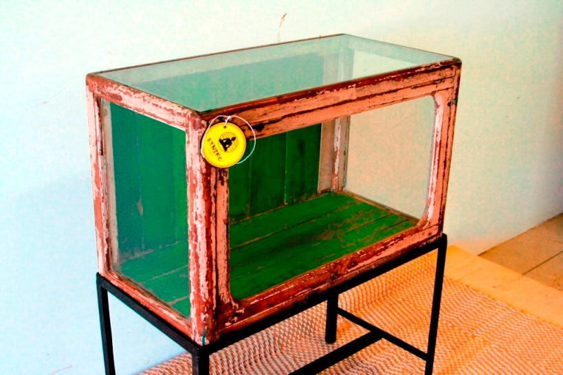 Vetrina, credenza , base indiana con basamento in metallo, vetro frontale e laterale. Usato come vetrina in negozio, apertura frontale a ribalta.  Dipinto interamente nella parte esterna la finitura è sbiancata, nella parte interna di verde intenso. Databile prima metà del '900. Pezzo unico. Dimensioni 75x40xh95cm. 